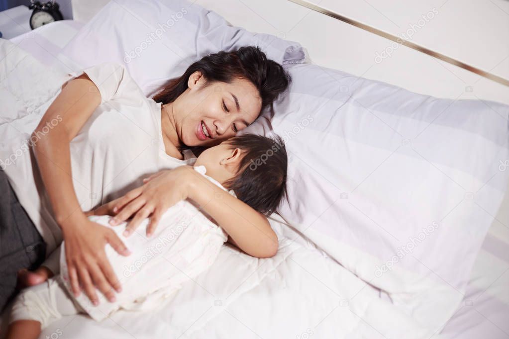 mother and baby sleeping on bed at home