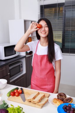 Neşeli kadın gözü ile mutfak oda içinde domates koruyor