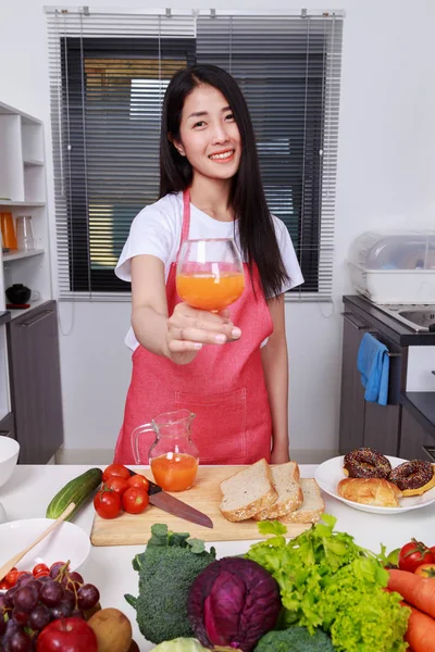 Mulher com um copo de suco de laranja na sala de cozinha — Fotografia de Stock
