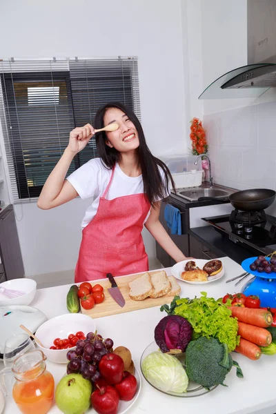 Mulher alegre está cobrindo seu olho com colher na sala da cozinha — Fotografia de Stock