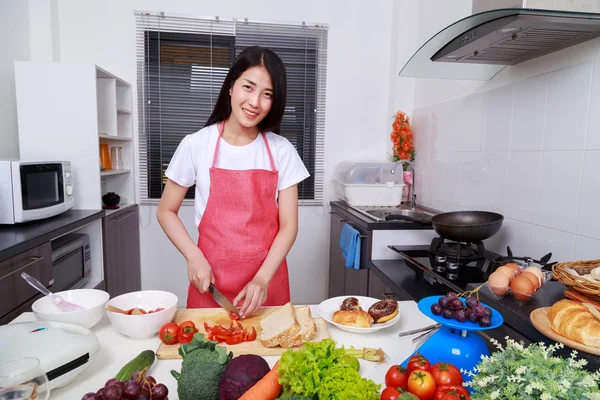 Mulher cortando tomate a bordo na sala de cozinha — Fotografia de Stock