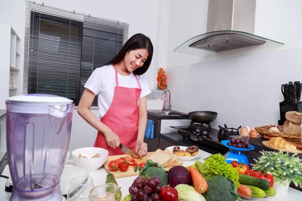 Mulher cortando tomate a bordo na sala de cozinha — Fotografia de Stock