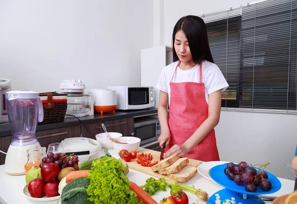 Mulher cortando tomate a bordo na sala de cozinha — Fotografia de Stock