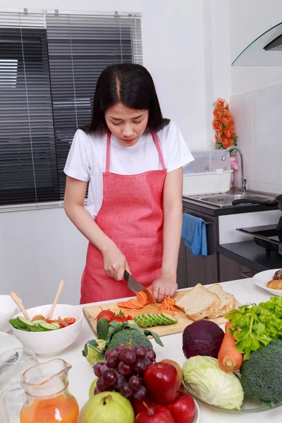 Mulher cortando cenoura na sala de cozinha — Fotografia de Stock