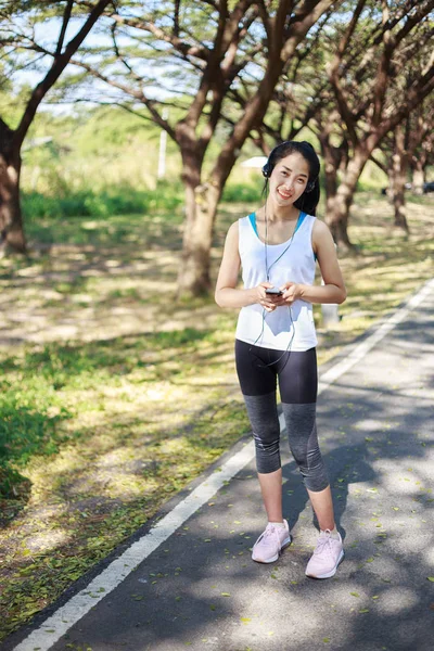 공원에서 헤드폰으로 스마트폰을 사용 하 여 젊은 스포티 한 여자 — 스톡 사진