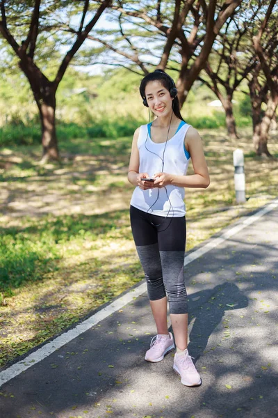 Jeune femme sportive utilisant un smartphone avec casque dans le parc — Photo