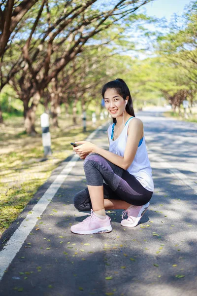 公園では、道路上に座っていると smartphon を使用してスポーティな女性 — ストック写真