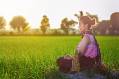 gün batımında, Tayland under yeşil pirinç içinde oturan çiftçi kadın