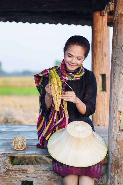 Campesina sosteniendo arroz y sentada en casa de campo en el campo de arroz —  Fotos de Stock