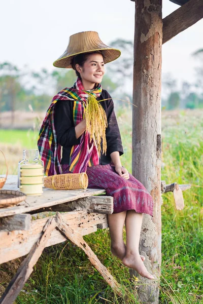 Farmer woman holding rice and sitting in cottage at rice field — Stock Photo, Image