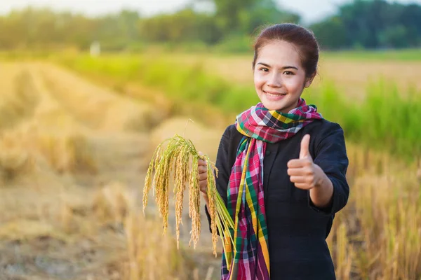 Woman showing thumb up and holding rice in field — Stock Photo, Image