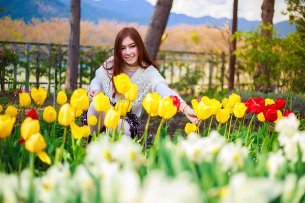 Hermosa mujer con tulipanes flores en el jardín — Foto de Stock