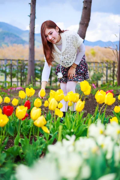 Hermosa mujer con tulipanes flores en el jardín — Foto de Stock