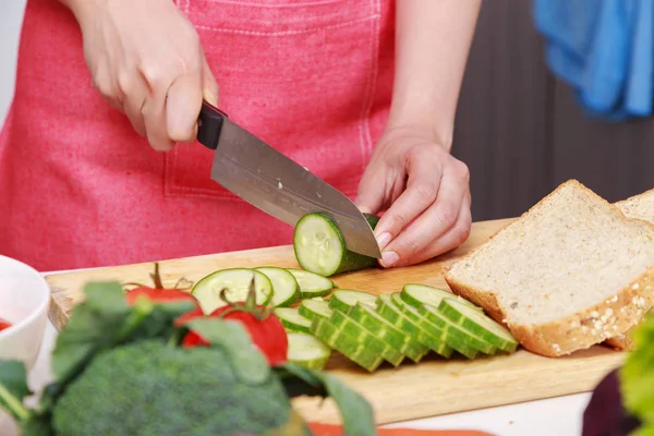 Hand cutting cucumber on board in kitchen room — Stock Photo, Image