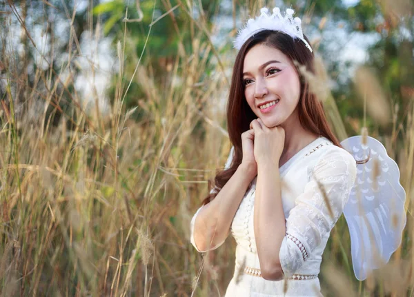 Mulher anjo em um campo de grama com luz solar — Fotografia de Stock