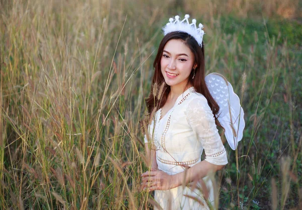 Mulher anjo em um campo de grama com luz solar — Fotografia de Stock