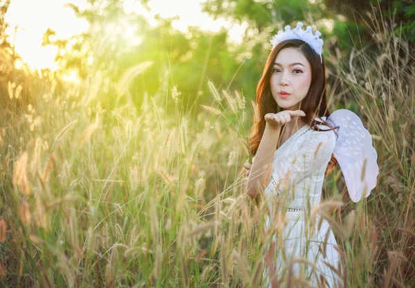 Mulher anjo em um campo de grama com luz solar — Fotografia de Stock