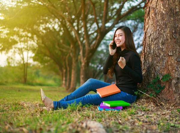 Gladlynt kvinna pratar i mobiltelefon med hand upp i park — Stockfoto