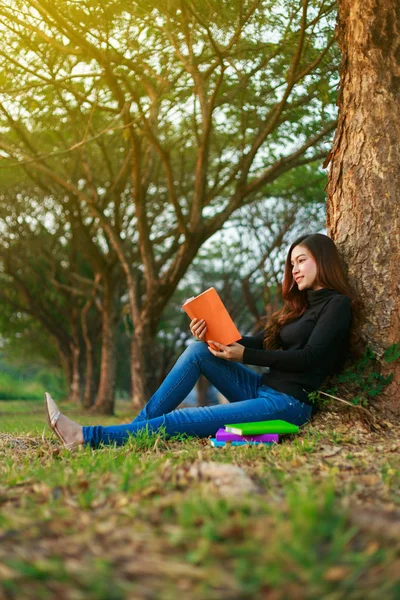 Ung kvinna sitta och läsa en bok i parken — Stockfoto