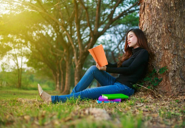 Ung kvinna sitta och läsa en bok i parken — Stockfoto