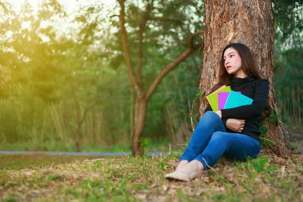 Giovane donna seduta e con in mano un libro nel parco — Foto Stock