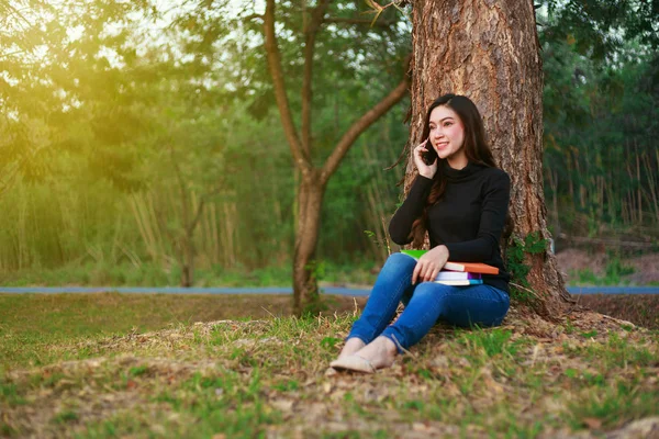 Leende kvinna talar i mobiltelefon i park — Stockfoto