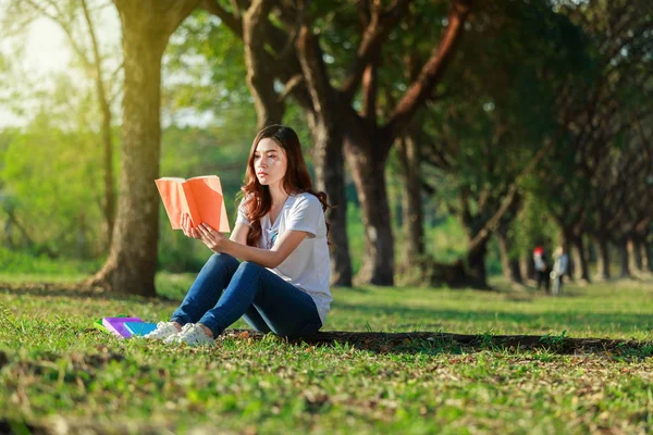 Kvinna sitter och läser en bok i parken — Stockfoto