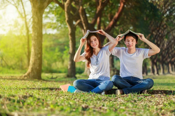 Couple holding a book and resting in park — Stock Photo, Image