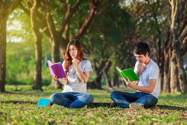Man och kvinna sitta och läsa en bok i parken — Stockfoto