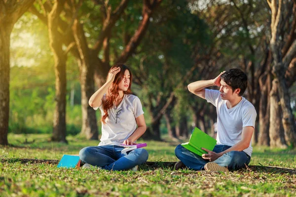 Uomo e donna seduti a leggere un libro nel parco — Foto Stock