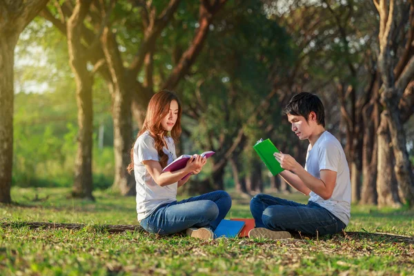 Man och kvinna sitta och läsa en bok i parken — Stockfoto