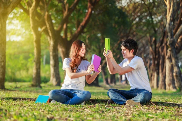 Couple holding a book and resting in park — Stock Photo, Image