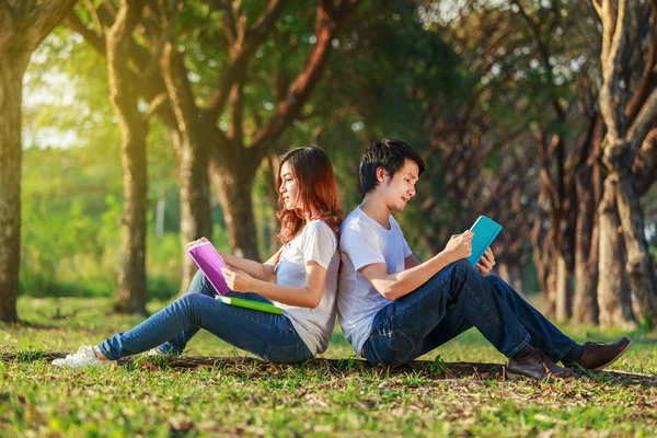 Άνδρας και γυναίκα κάθεται και διαβάζοντας ένα βιβλίο στο πάρκο — Φωτογραφία Αρχείου