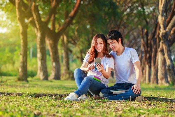 Couple using mobile phone in park — Stock Photo, Image