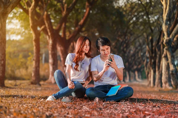 Para przy użyciu telefonu komórkowego w parku — Zdjęcie stockowe
