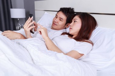 Genç çift yatak yatak odasında cep telefonu kullanma