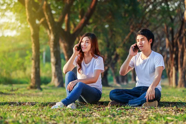 Par som pratar i mobiltelefon i parken — Stockfoto