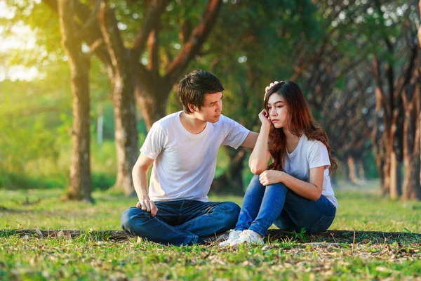 Unhappy woman sitting with a concerned guy comforting her in par — Stock Photo, Image