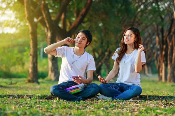 Paar hört Musik vom Handy mit Kopfhörer im Park — Stockfoto