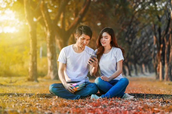 Pareja escuchando música desde el móvil con auriculares en el parque — Foto de Stock