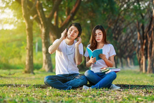 Giovane coppia che legge un libro e ascolta musica con le cuffie i — Foto Stock