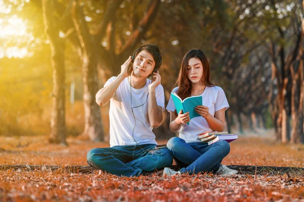 Joven pareja leyendo un libro y escuchando música con auriculares i —  Fotos de Stock