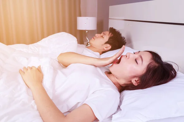 Mujer bostezando y su marido durmiendo en la cama — Foto de Stock