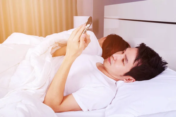 Homme utilisant son téléphone portable au lit pendant que sa femme dort nex — Photo