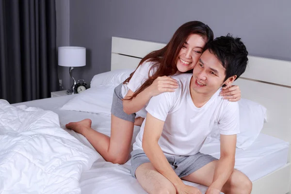 Glada unga attraktiva par kramas på sängen i sovrummet — Stockfoto