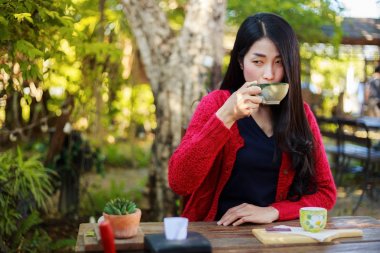 bir masada oturan ve bir fincan kahve gard içinde içme kadın