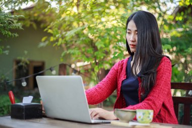 dizüstü bilgisayar kullanarak ve bahçesinde kahve içme genç kadın