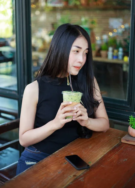 Женщина обедает латте со льдом зеленый чай в кафе — стоковое фото