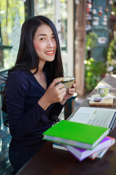 Femme utilisant un ordinateur portable au café tout en buvant du café — Photo