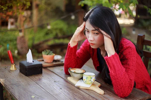 Worried woman with a cup of coffee in the garden — Stock Photo, Image